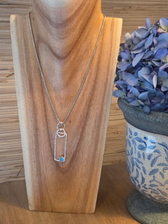 Geometric silver pendant necklace displayed on a wood bust